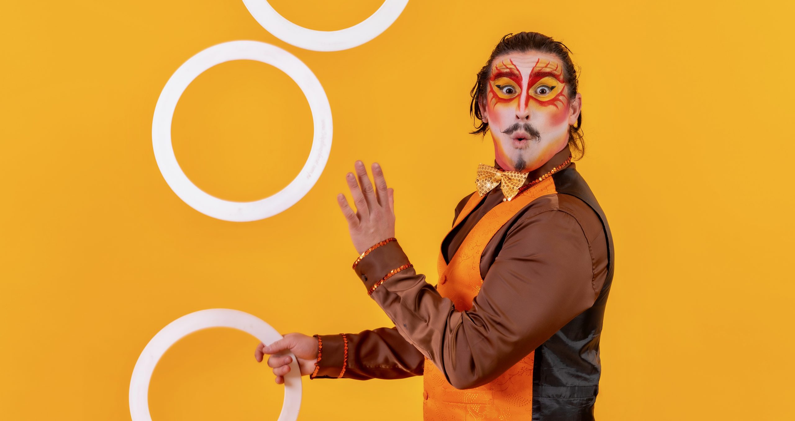 Picture of a man in costume juggling rings